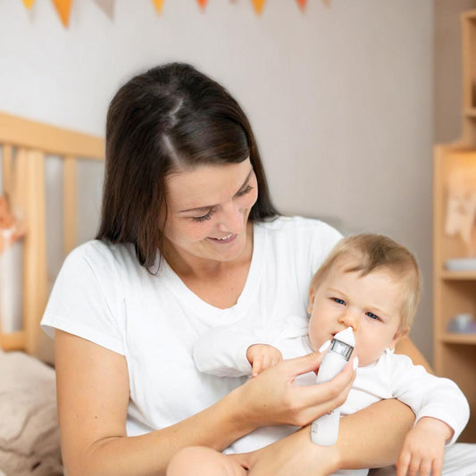 Mor som hjelper babyen med å rense nesen ved bruk av Luumii BabyGo elektrisk nesesuger.