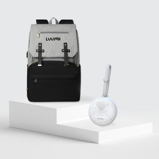 Luumii stelleveske i grå og svart sammen med bærbar white noise maskin for baby, presentert på hvitt podium