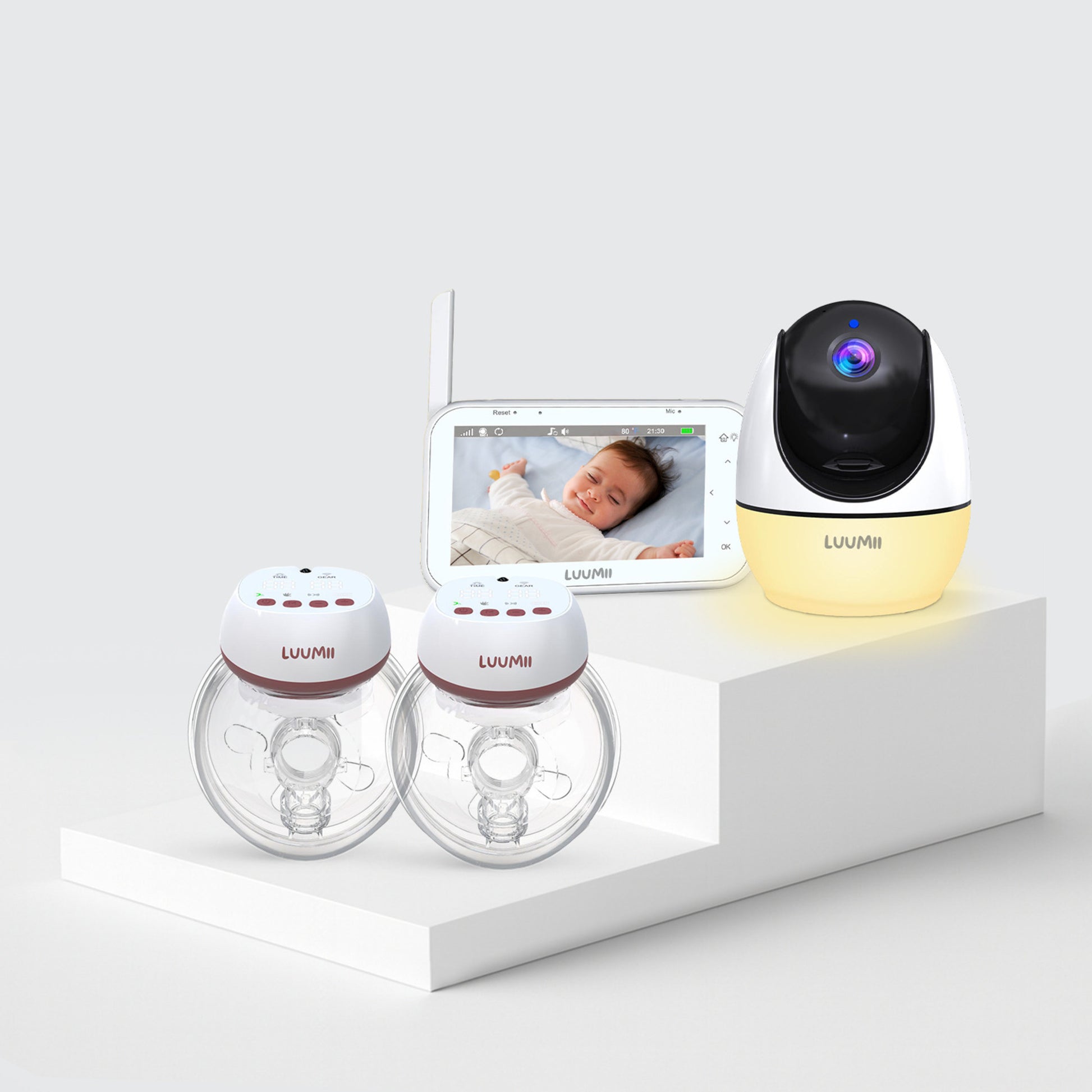 Luumii dobbel bærbar brystpumpe, babymonitor med skjerm og  kamera med nattlys, presentert på hvitt podium.
