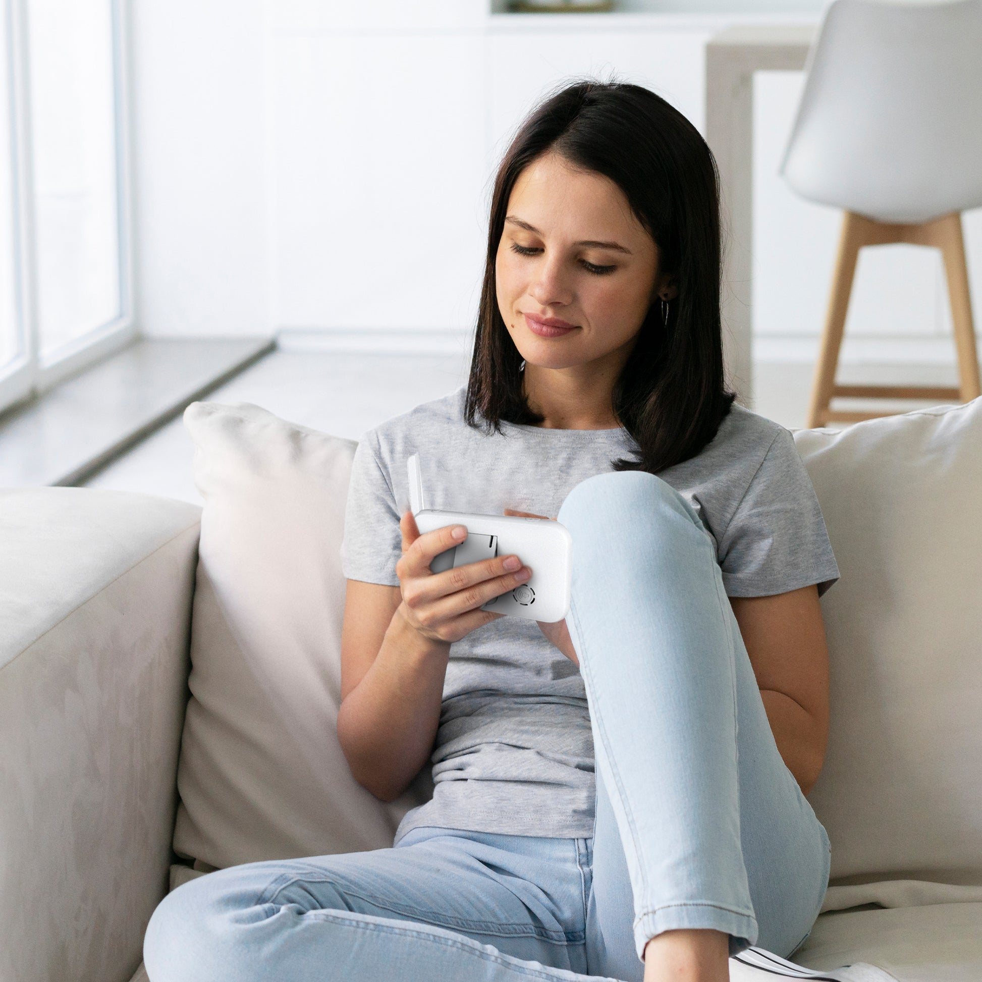 Mamma sitter i sofaen og følger babyen på Luumii babymonitor-skjermen