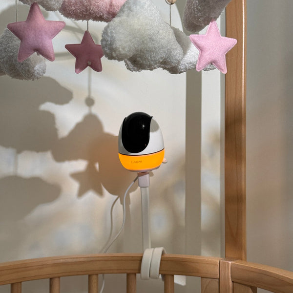 Luumii babymonitor med nattlys i babyseng under rosa stjerneleker