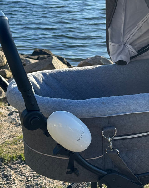 Luumii baby rocker festet på barnevogn under trilletur ved vannet