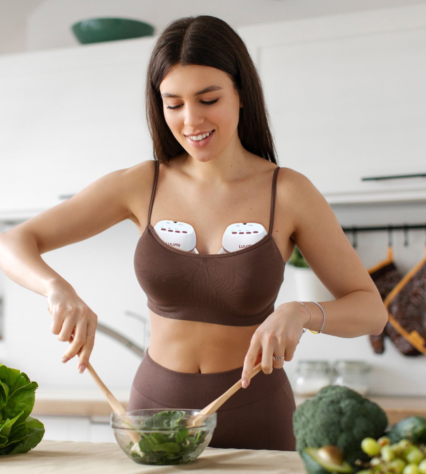 Kvinne som bruker Luumii bærbar brystpumpe mens hun lager mat på kjøkkenet