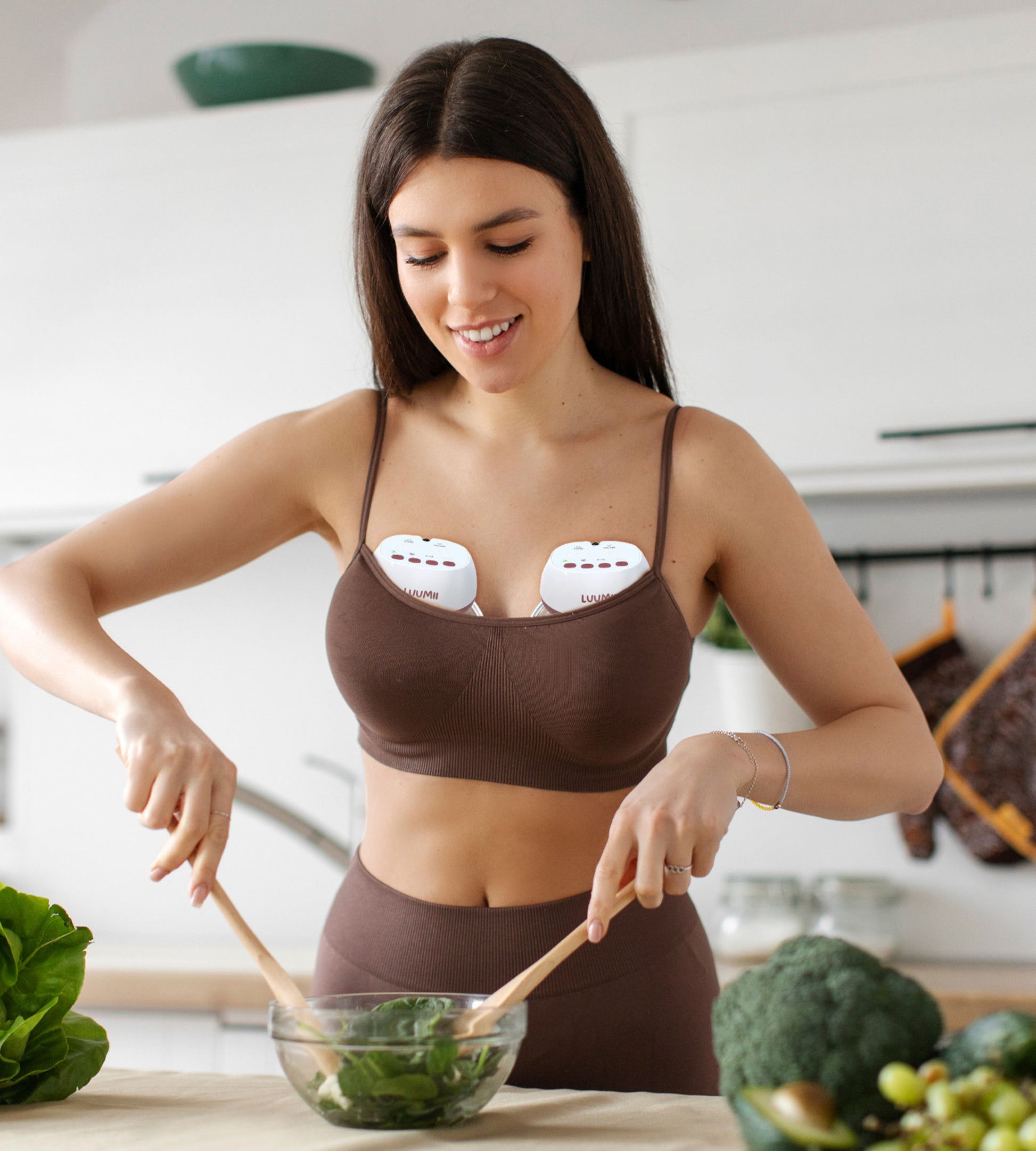 Kvinne som bruker Luumii bærbar brystpumpe mens hun lager mat på kjøkkenet